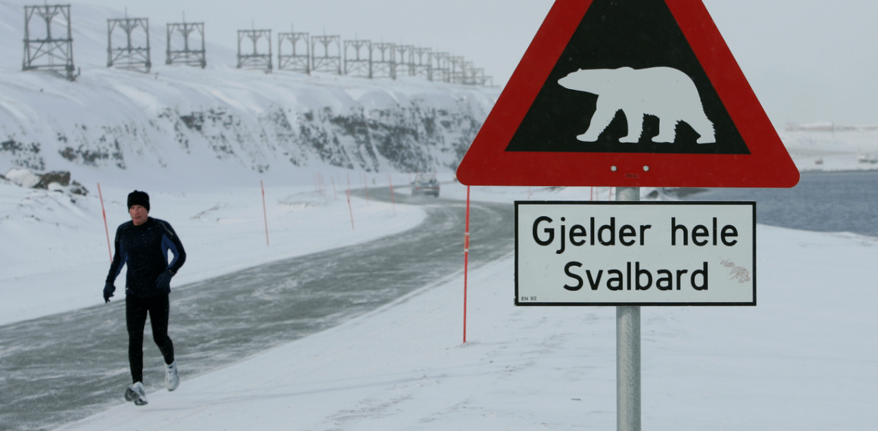 A runner passes a sign warning of the dangers of polar bears on the Norwegian Arctic archipelago of Svalbard. Credit: Reuters Photo