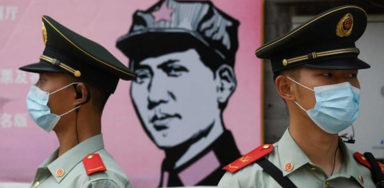 Paramilitary police officers stand guard in front of a poster of late communist leader Mao Zedong on a street south of the Great Hall of the People. Credit: AFP Photo