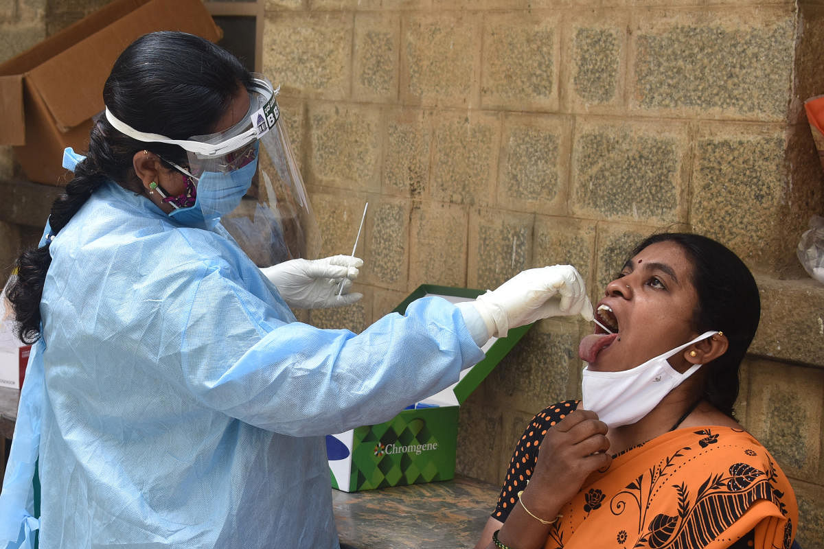 A BBMP health staffer conducts Covid-19 tests at NR Colony on Thursday. DH Photo/S K Dinesh