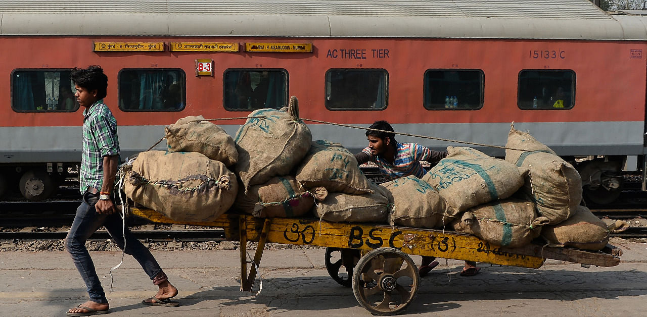  Indian labourers transport goods loaded on a handcart at a railway station in New Delhi. Credit: AFP File Photo
