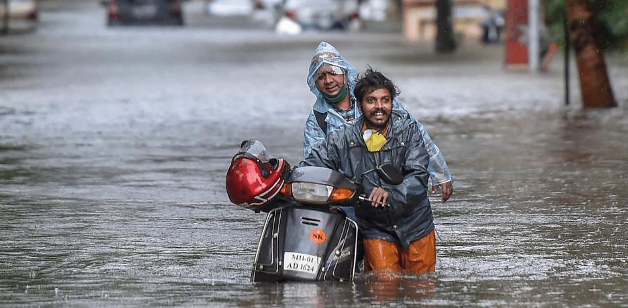 Commuters wade through a waterlogged street following heavy rainfall. Credit: PTI