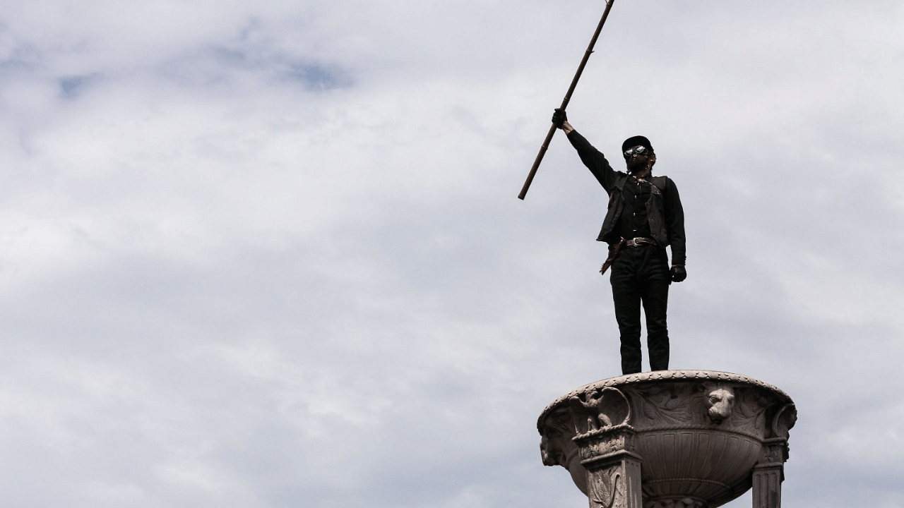 A demonstrator stands atop the Lincoln Memorial holding a flag during the Commitment March. Credits: AFP Photo