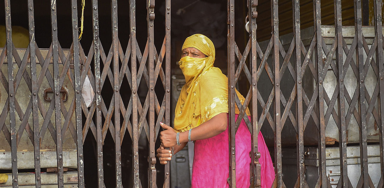 A woman closes the gate of a shop during the biweekly lockdown in the wake of coronavirus pandemic, in Kolkata, Thursday. Credit: PTI