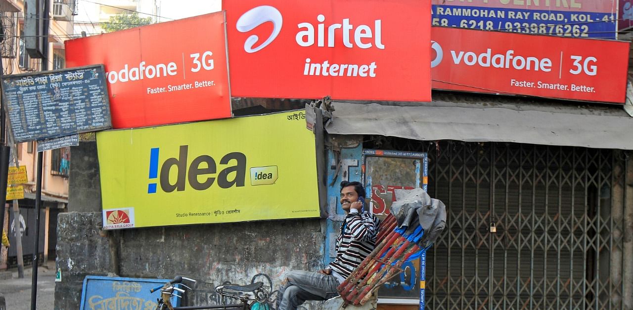 A rickshaw puller speaks on his mobile phone in front of advertisement billboards belonging to telecom companies. Representative Photo. Credit: Reuters
