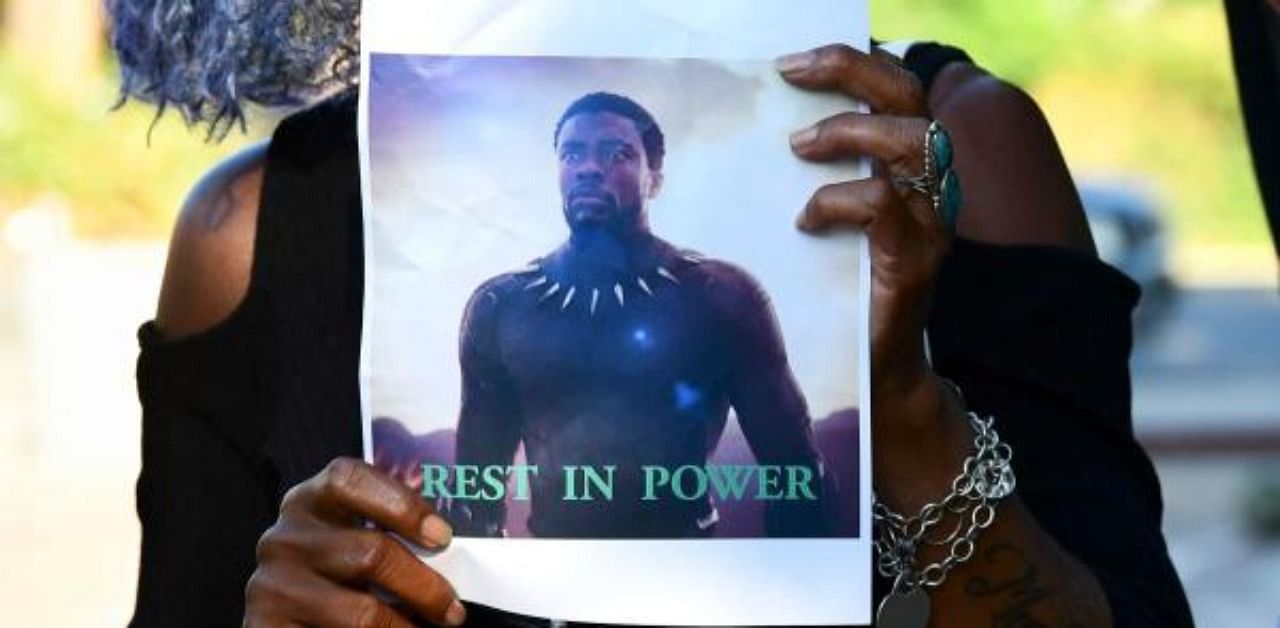 A woman holds a photograph of the late US actor and producer Chadwick Boseman during a candlelight vigil held by fans in Los Angeles. Credit: AFP