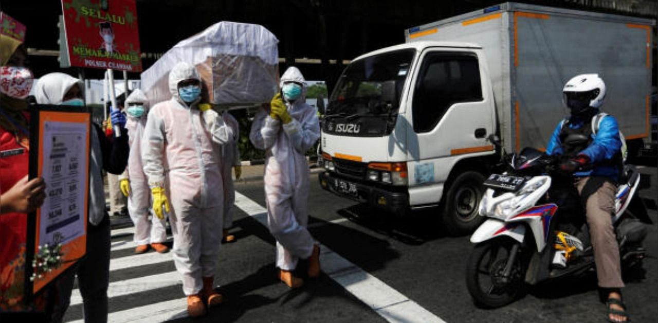 Government workers wearing protective suits carry a mock-up of a coffin of a coronavirus disease victim. Credit: Reuters