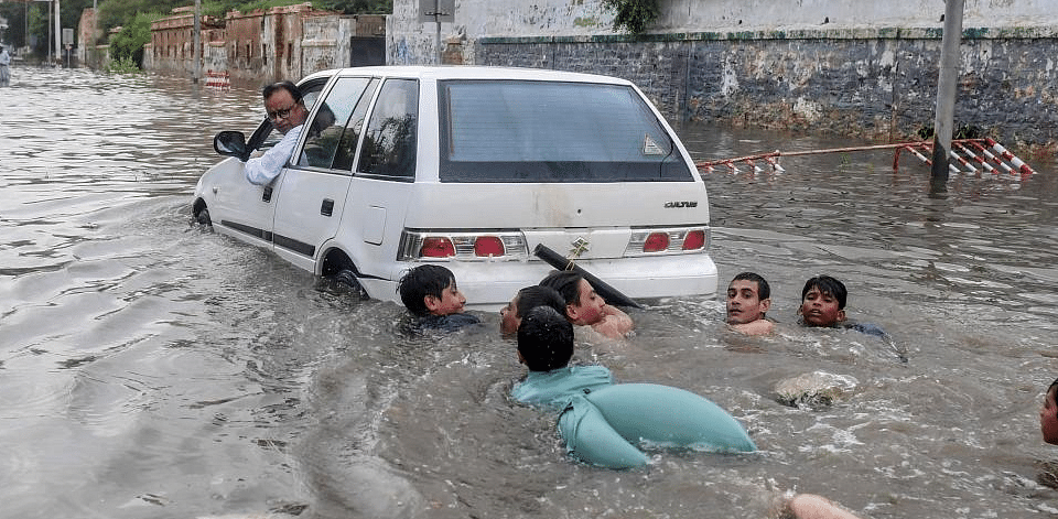 Youths swim in the main flooded I. I. Chundrigar Road located in central business district of Karachi. Credit: AFP