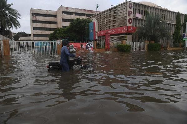 A milkman rides on his bike through the main flooded I. I. Chundrigar Road located in central business district of Karachi. Credit: AFP Photo