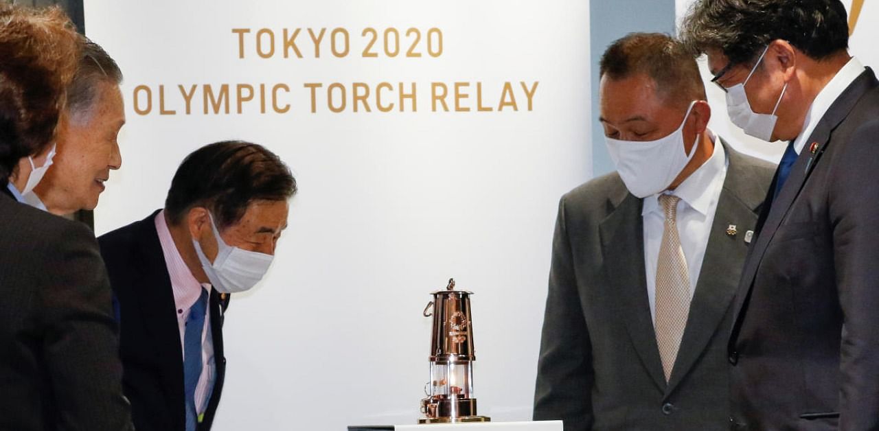 Representatives of the Tokyo Organising Committee of the Olympic and Paralympic Games (Tokyo 2020) and the Japanese Olympic Committee look at the Olympic Flame. Credits: Reuters