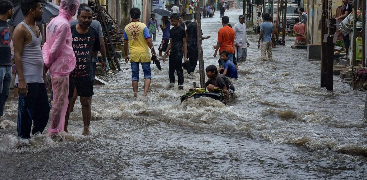 People cross a flooded street after heavy rain, in Rajkot. Credits: PTI