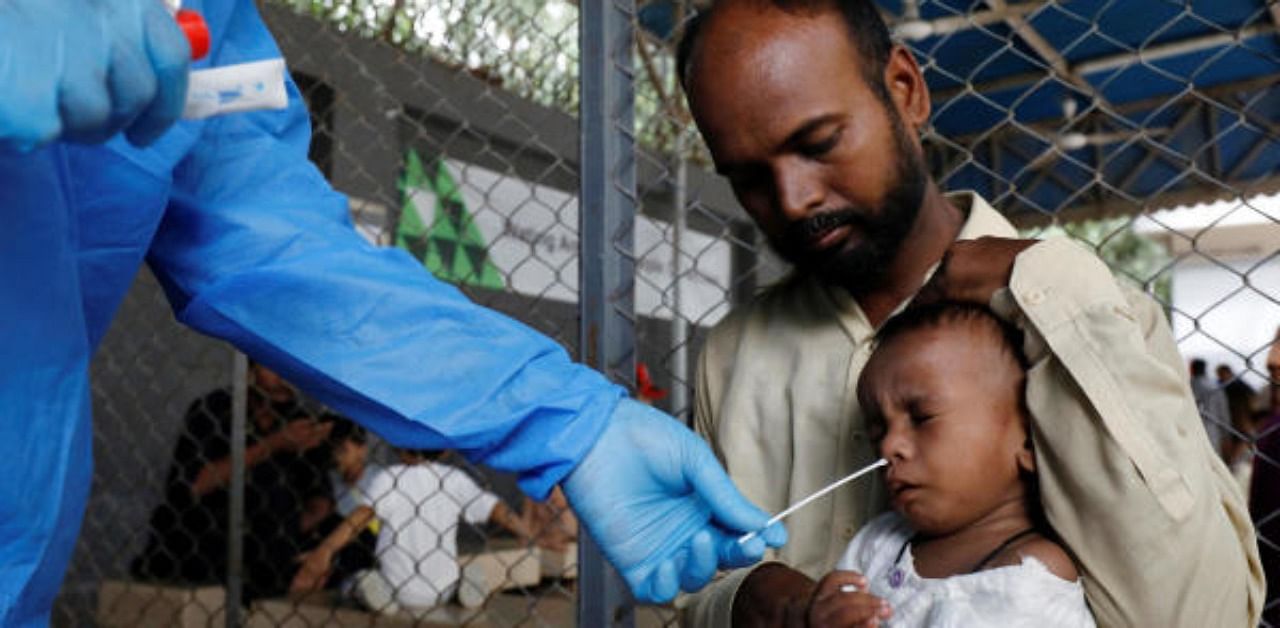 A healthcare worker takes a swab sample from a child to be tested for the coronavirus disease in Karachi, Pakistan. Credit: Reuters