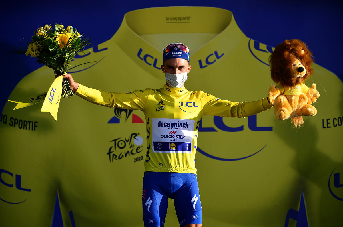 Deceuninck-Quick Step rider Julian Alaphilippe of France, wearing the overall leader's yellow jersey, celebrates on the podium. Credit: Reuters