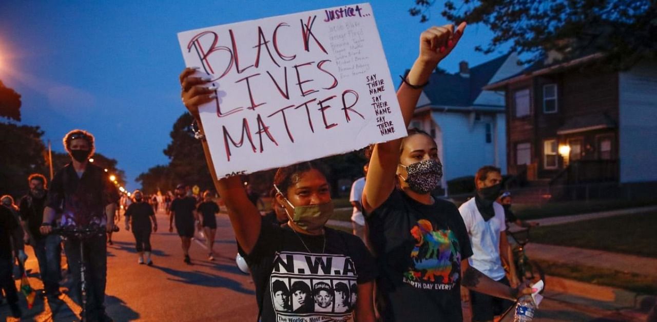 A protester holds a Black Lives Matter sign during a demonstration against the shooting of Jacob Blake in Kenosha. Credits: AFP