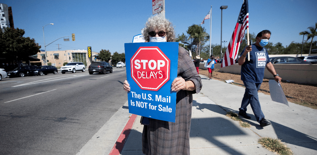 Activist Aixa Fielder holds a sign during a rally outside the USPS Bicentennial Post Office calling for an end to mail delays, funding for the Postal Service and for the firing of US Postmaster General Louis DeJoy. Credit: Reuters Photo