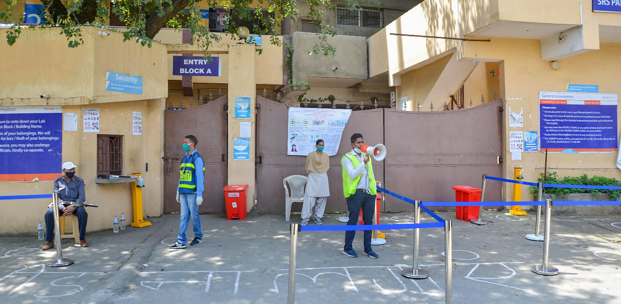 A worker makes announcements on a loudspeaker as students begin to gather outside Tata Consultancy Services Limited (TCS), alloted to conduct JEE entrance exams, amid the ongoing coronavirus pandemic, in Ranchi. Credit: PTI Photo