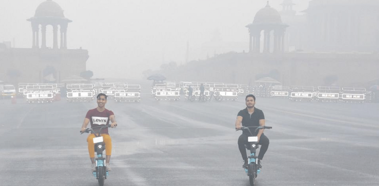 Commuters ride on Rajpath amid heavy smog, in New Delhi. Credit: PTI