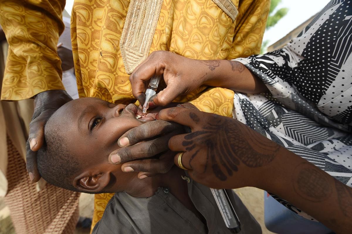(FILES) In this file photo taken on April 22, 2017 A Health worker administers a vaccine to a child during a vaccination campaign against polio at Hotoro-Kudu, Nassarawa district of Kano in northwest Nigeria. - The World Health Organization (WHO) is to ce