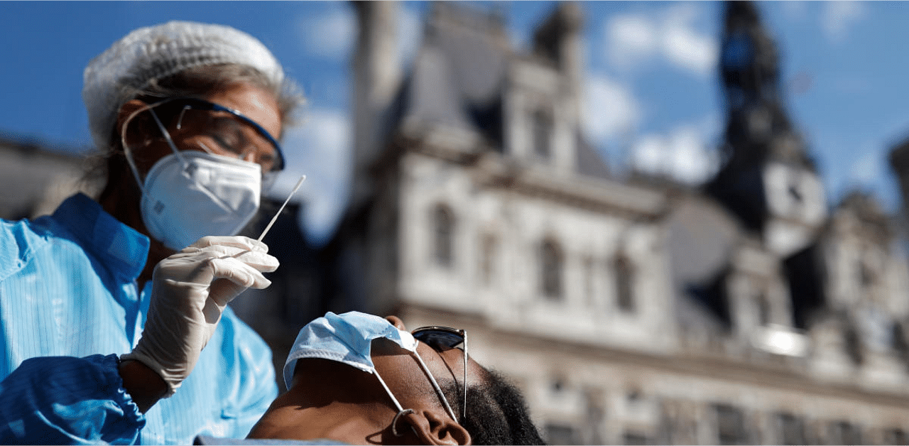 A health worker, wearing a protective suit and a face mask, prepares to administer a nasal swab to a patient at a testing site for the coronavirus disease in Paris. Credit: Reuters