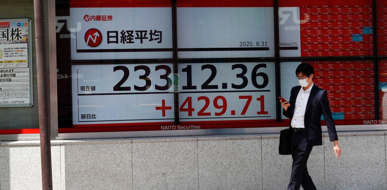 A man walks past a screen showing Nikkei index outside a brokerage in Tokyo. Credits: Reuters