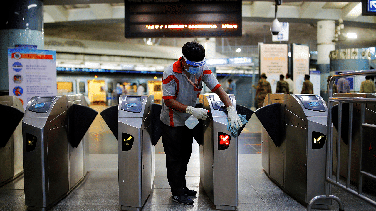 A worker cleans the entry gates at a Delhi Metro station ahead of the restart of its operations, amidst the spread of coronavirus disease. Credits: Reuters Photo