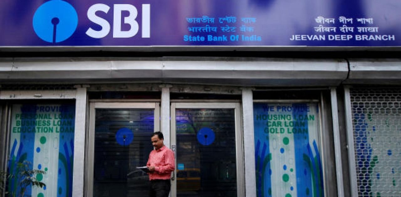  A man checks his mobile phone in front of State Bank of India (SBI) branch. Representative Photo. Credit: Reuters