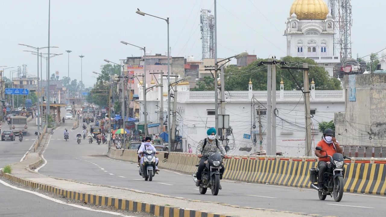 Commuters ride along a road after the government imposed lockdown norms in the state for weekends and public holidays as a preventive measure against the Covid-19 coronavirus, on the outskirts of Amritsar. Credit: PTI