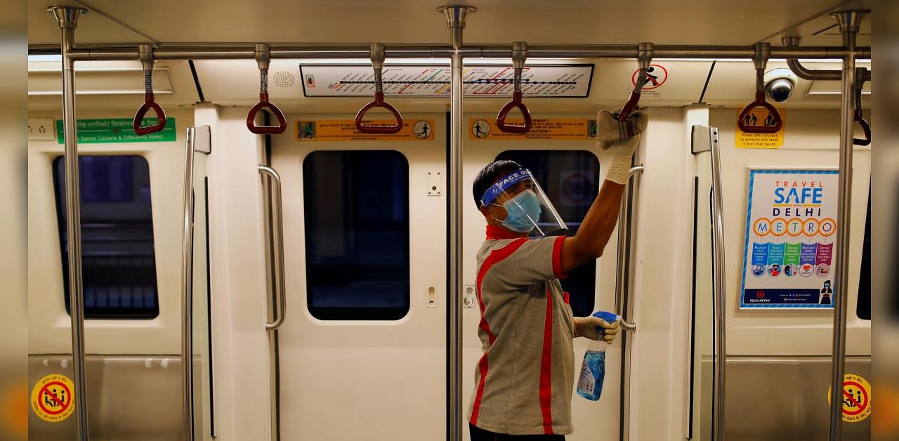A worker wearing a face shield and mask cleans handles inside a train at a Delhi Metro station ahead of the restart of its operations, amidst the spread of coronavirus Iin Nrew Delhi. Credit: Reuters