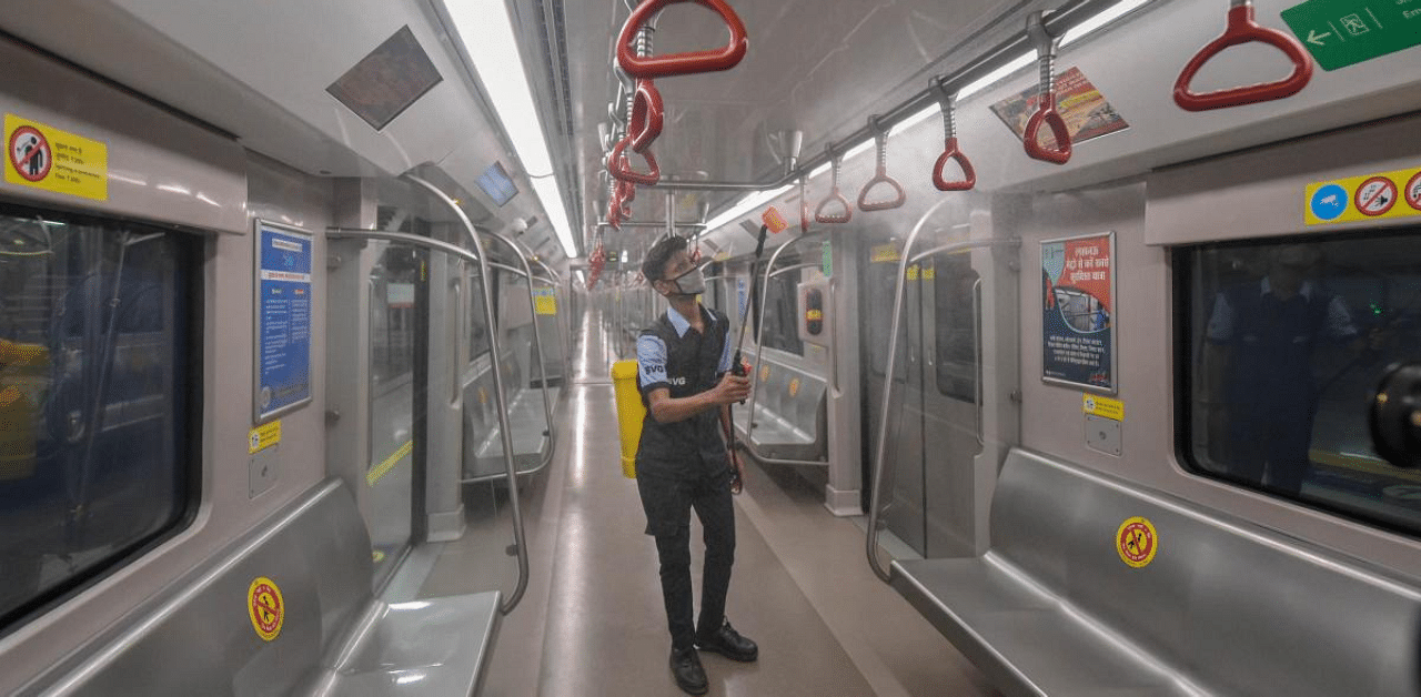 A Lucknow Metro employee sprays disinfectant inside a metro, as authorities prepare to resume services from Sept. 7, at Hazratganj metro station in Lucknow. Credit: PTI Photo