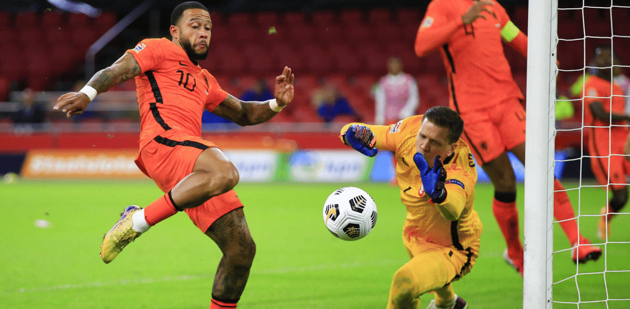 Netherlands' Memphis Depay, left, kicks at the ball as Poland's goalkeeper Wojciech Szczesny reaches out to block the shot during the UEFA Nations League soccer match between the Netherlands and Poland in the Johan Cruyff ArenA in Amsterdam. Credit: AP Photo
