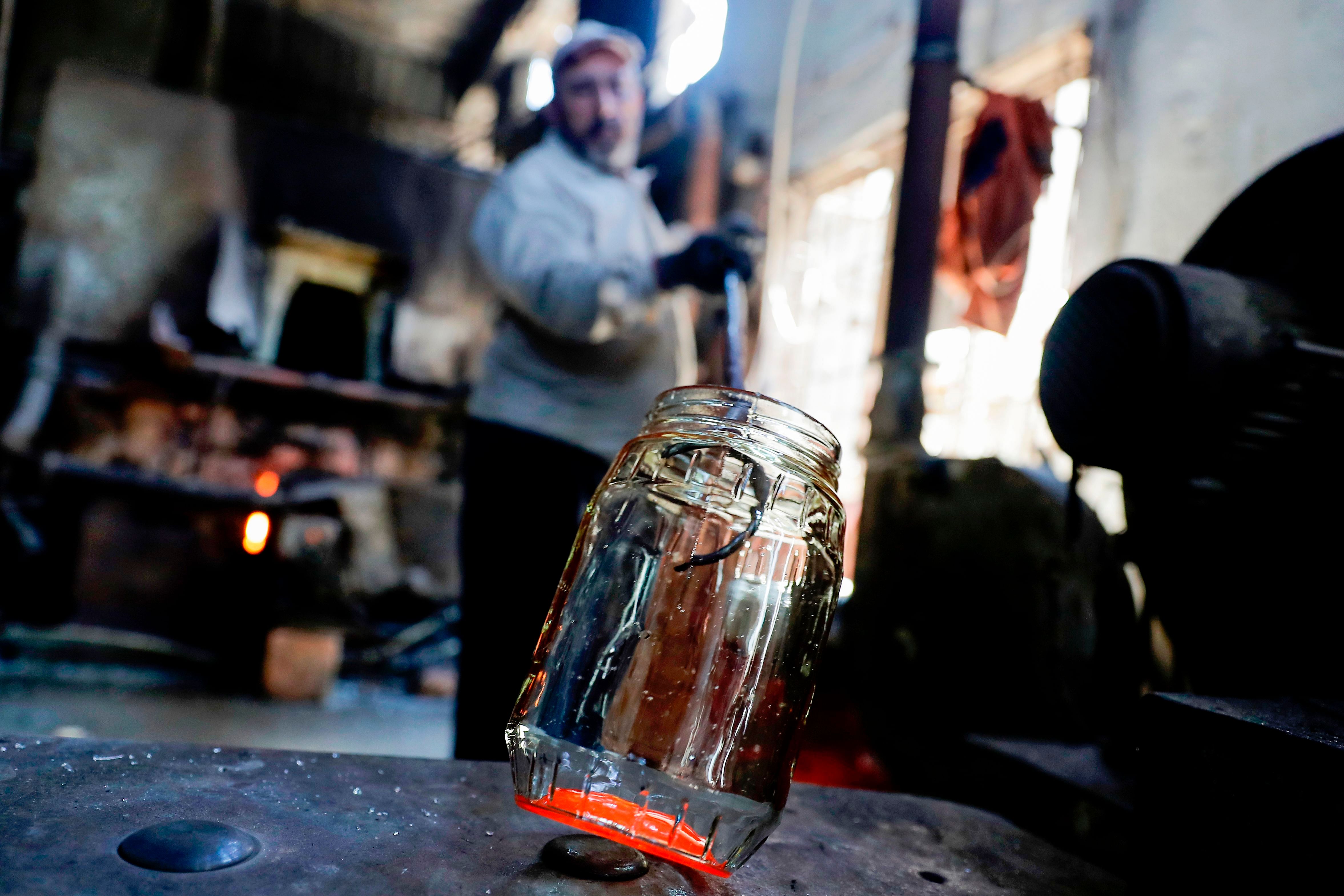 A glassblower forms glass at factory, which is recycling the broken glass as a result of the Beirut explosion, in the northern Lebanese port city of Tripoli on August 25, 2020. - The August 4 port explosion ripped through countless glass doors and windows when it laid waste to whole Beirut neighbourhoods, killing at least 190 people and wounding thousands more. Volunteers, non-governmental groups and entrepreneurs salvaged a fraction of the tonnes of broken glass that littered the streets, some of it through recycling at Wissam Hammoud's family's glass factory. Credit: AFP Photo