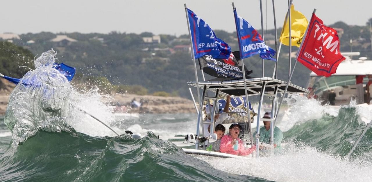 A boat is engulfed in waves from the large wakes of a flotilla of supporters of U.S. President Donald Trump, during a boat parade on Lake Travis near Lakeway, Texas. Credits: Reuters