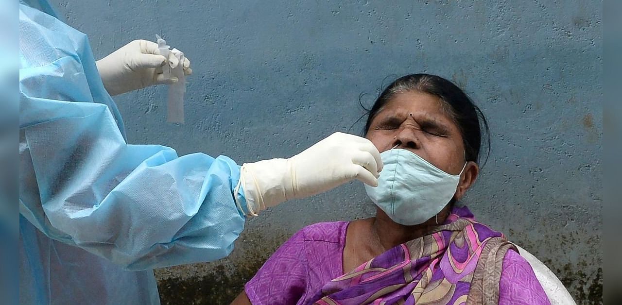 A health worker (L) wearing Personal Protective Equipment (PPE) suit collects a swab sample from a woman to test for the Covid-19 coronavirus, at a primary health centre in Hyderabad on September 4, 2020. Credit: AFP Photo