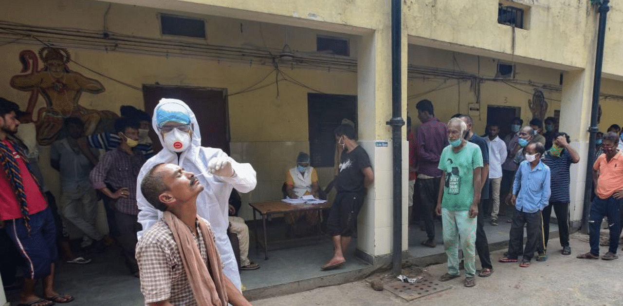   A health worker takes samples from a homeless man for Covid-19 test as others wait for their turn, in New Delhi. Credit: PTI