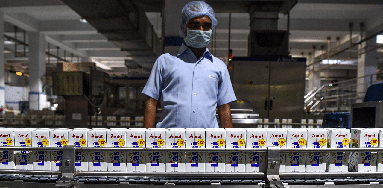 An Indian employee monitors tetra packs of lassi going through the production line at the Mother Dairy factory, which manufactures the Amul brand of ice cream, buttermilk, lassi at Bhatt village. Credit: AFP Photo
