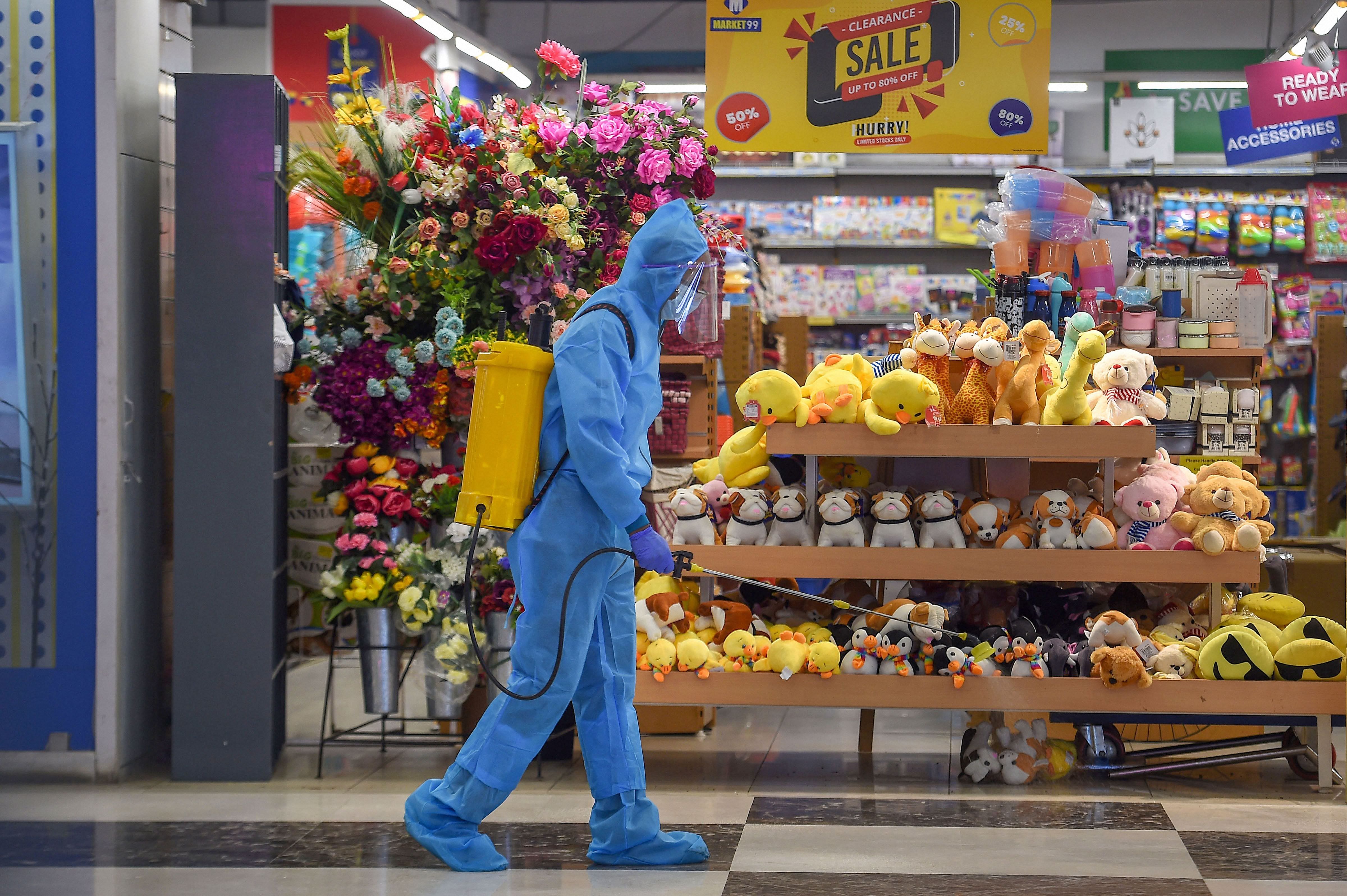 A worker wearing PPE kit sprays disinfectant inside a shopping mall after authorities eased restrictions during Unlock 4.0, in Chennai. Credit: PTI Photo