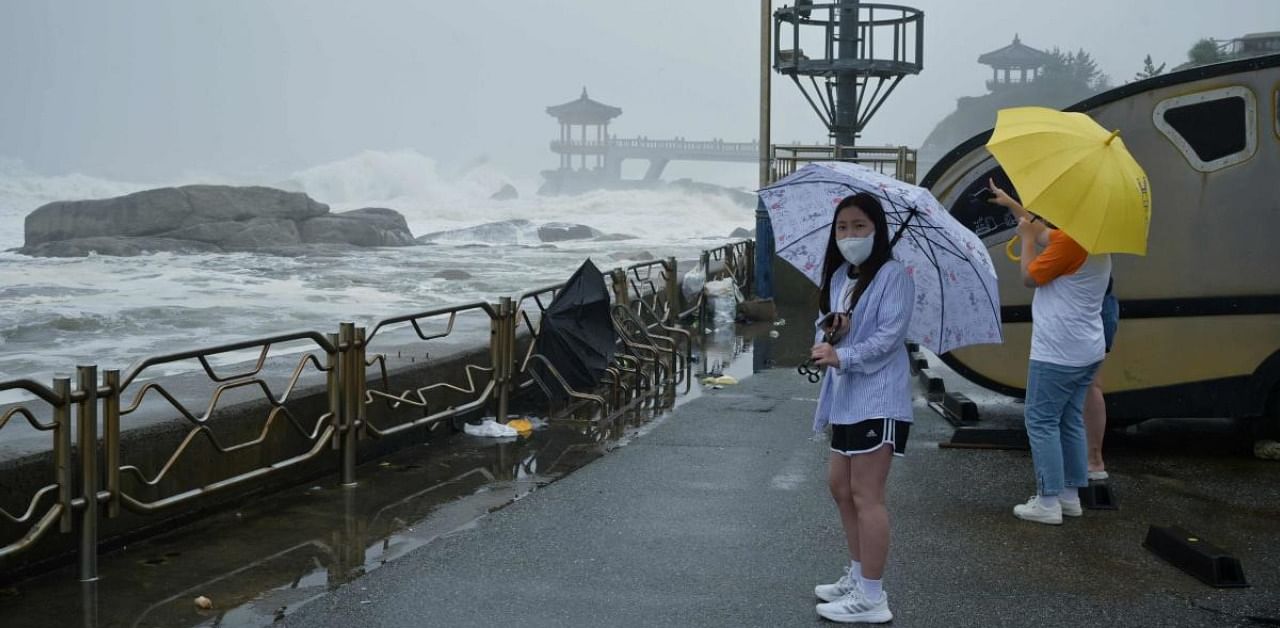 People stand before a sea wall to watch the waves brought by Typhoon Haishen in the eastern port city of Sokcho. Credits: AFP