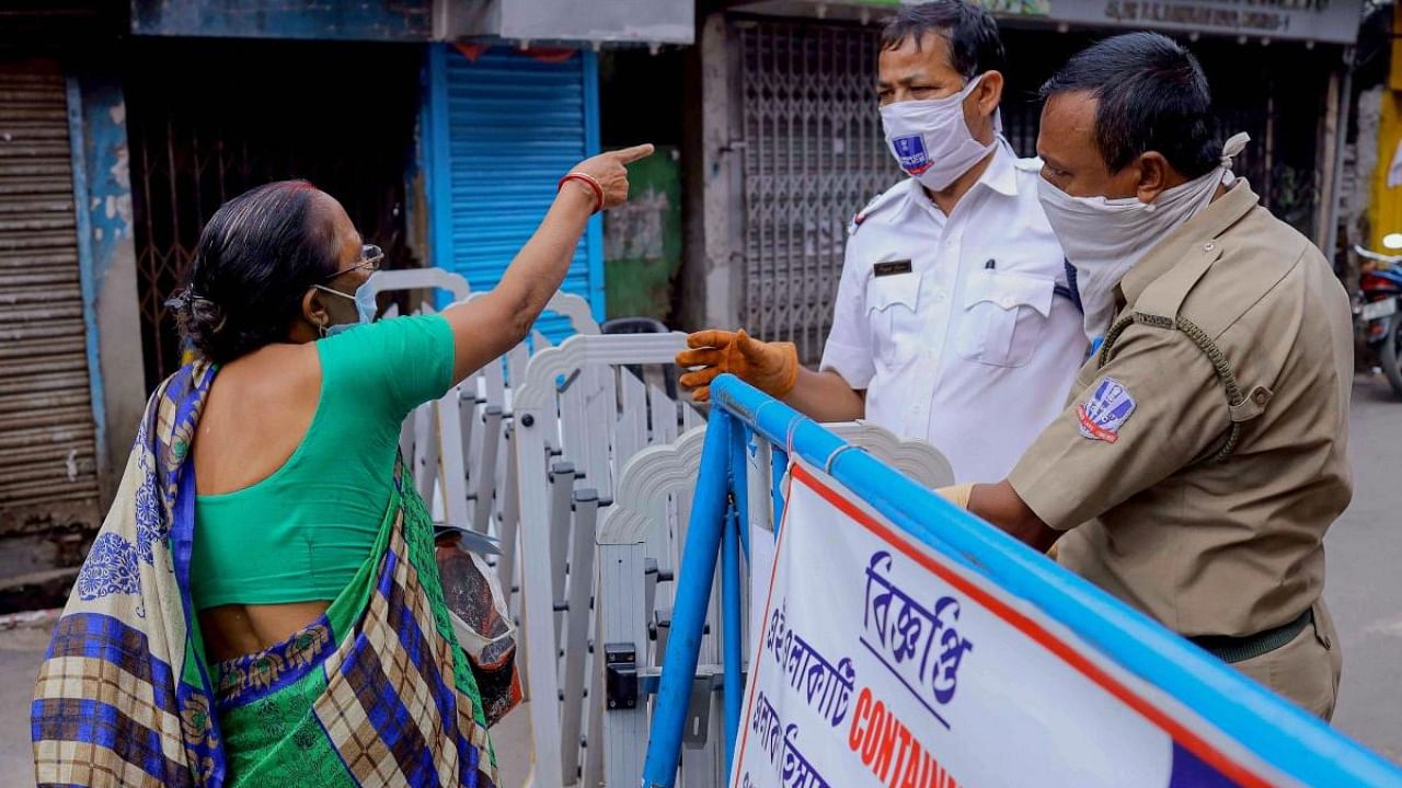 Policemen stop a commuter from entering at sealed residential area. Credit: PTI