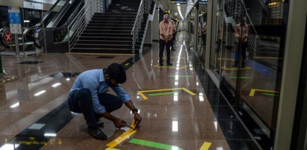 A worker fixes a social distancing marker on a platform during a media preview as the Chennai Metro network prepares to resume services partially after more than 5 months shutdown due to the Covid-19 coronavirus pandemic, at a metro station in Chennai. Credit: AFP Photo
