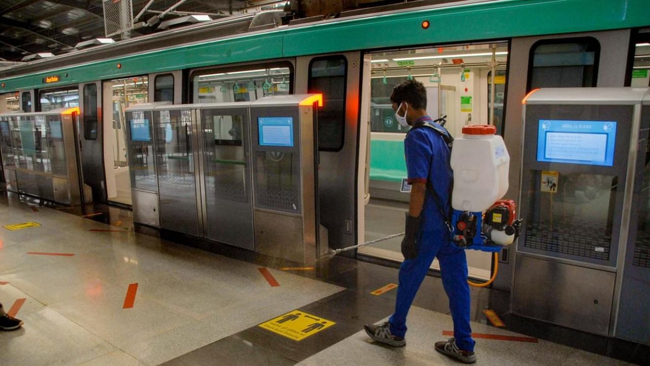 A Noida Metro Rail Corporation (NMRC) employee sprays disinfectants outside a metro, as authorities prepare to resume services, at Sector 51 metro station in Noida. Credit: PTI
