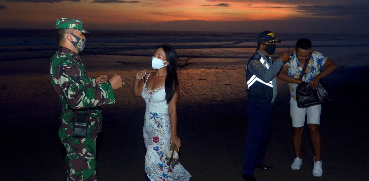 Officers wearing protective face masks give warning to visitors for wearing protective masks, amid the coronavirus disease outbreak in Badung, Bali. Credit: Reuters