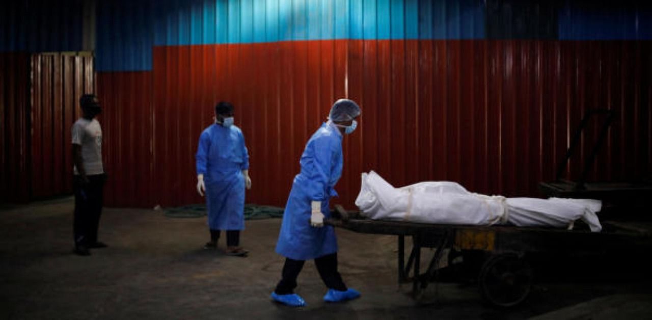 A health worker wearing personal protective equipment (PPE) carries the body of a man, who died due to the coronavirus disease. Credit: Reuters