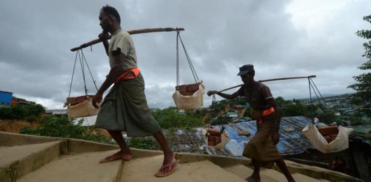 Rohingya men carry bricks on a hill for construction works in Jamtoli refugee camp, near Ukhia. Credit: AFP