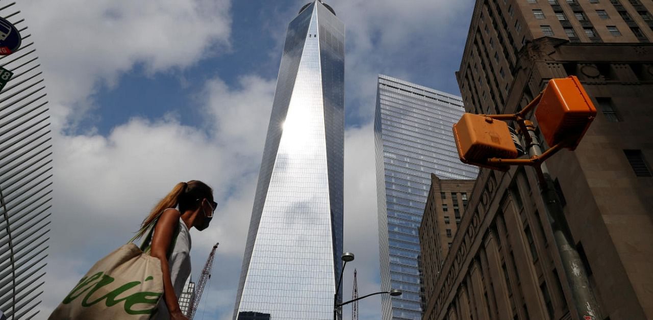 A woman wearing a protective face mask walks by One World Trade Center. Credit: Reuters