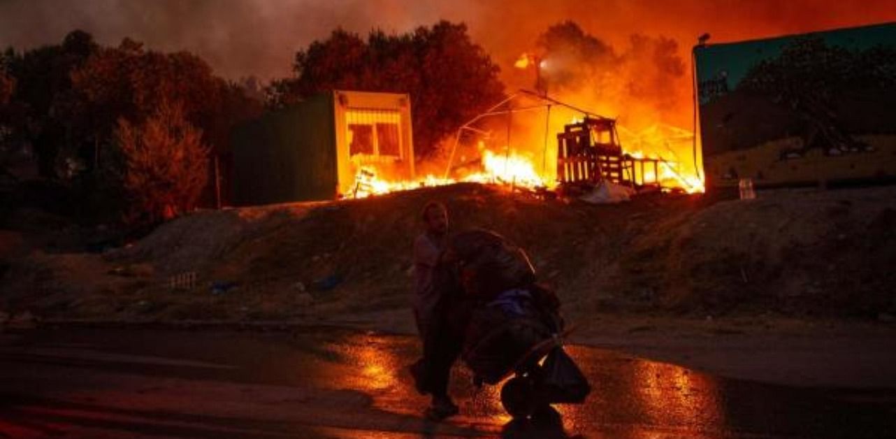 A man carrying belongings flees flames after a major fire broke out in the Moria migrants camp on the Greek Aegean island of Lesbos. Credit: AFP Photo