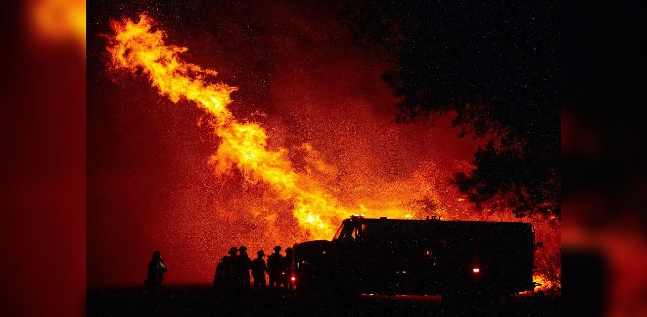 Butte county firefighters watch as flames tower over their truck at the Bear fire in Oroville, California on September 9, 2020. - Dangerous dry winds whipped up California's record-breaking wildfires and ignited new blazes, as hundreds were evacuated by helicopter and tens of thousands were plunged into darkness by power outages across the western United States. Credit: AFP Photo