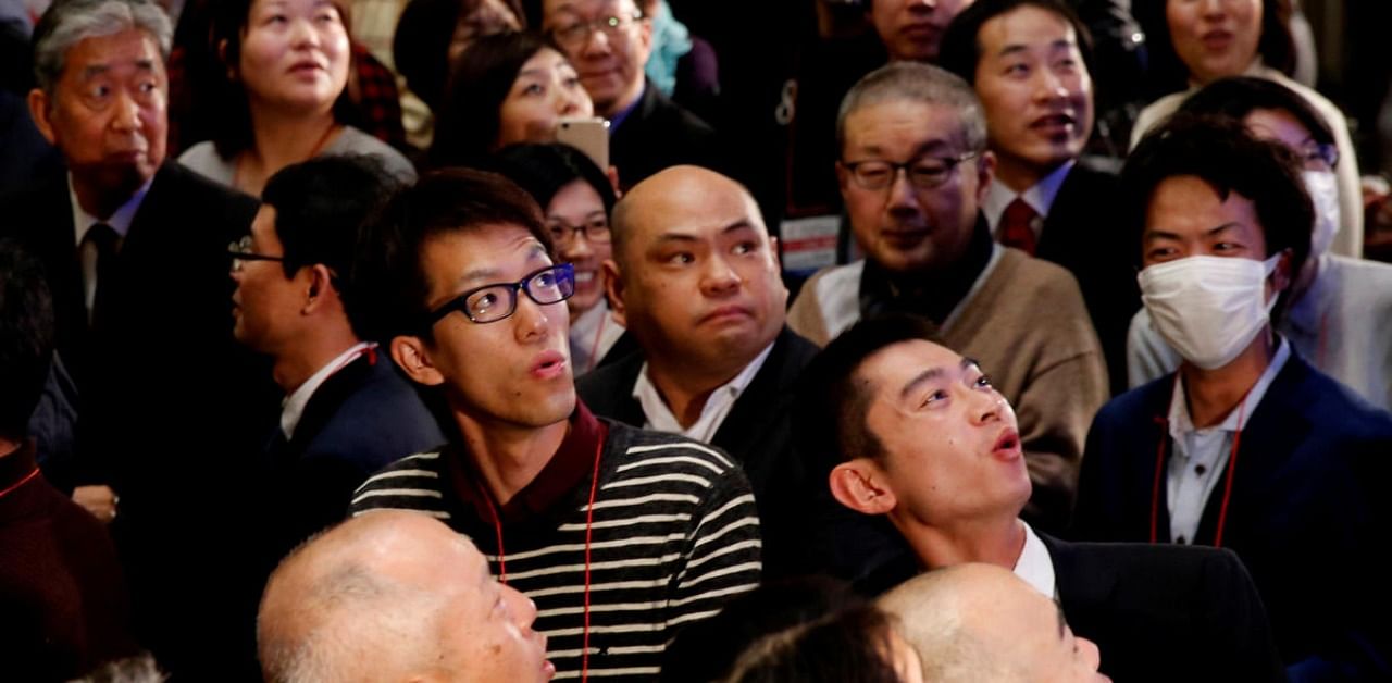 Attendees react as they look at the closing price of Nikkei index. Credit: Reuters
