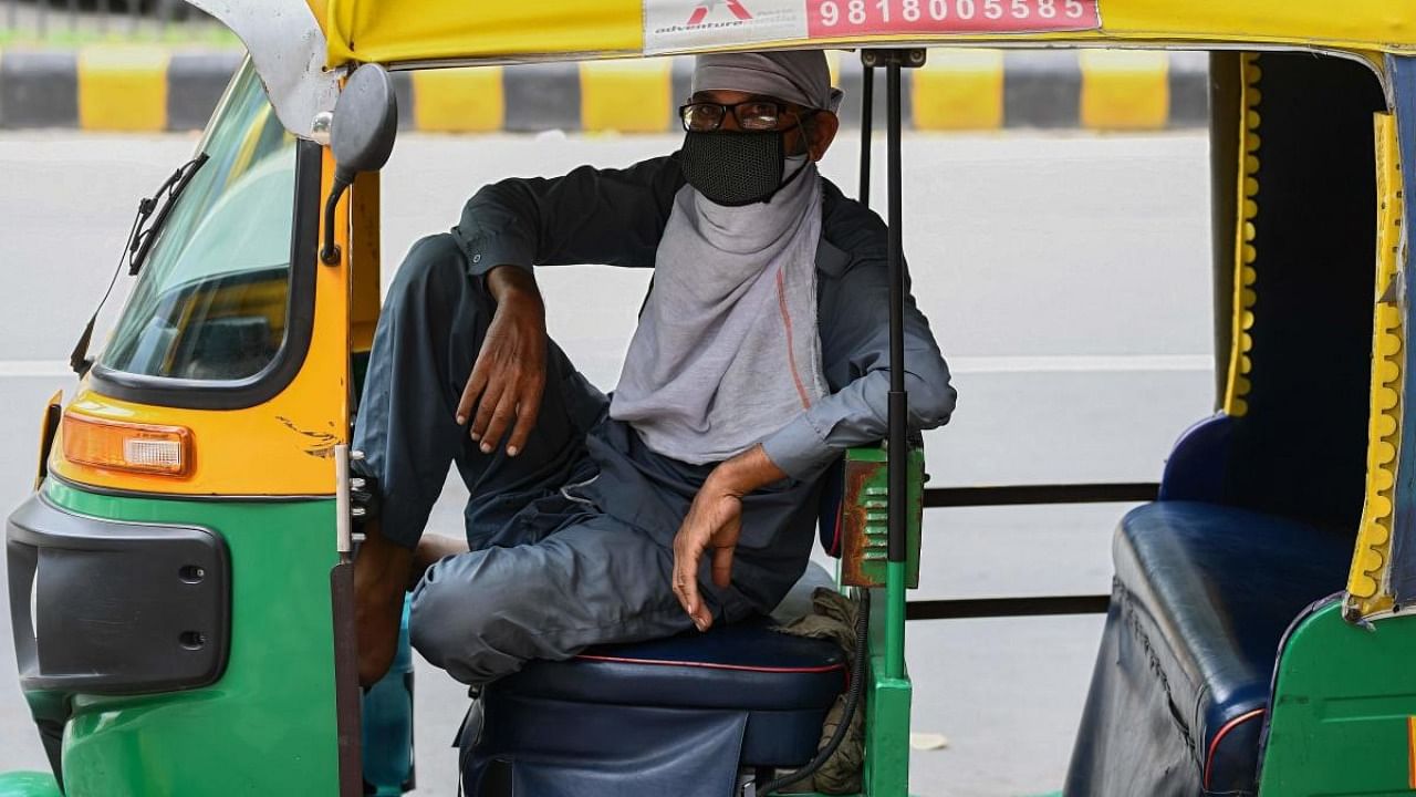 An auto rickshaw driver wearing a facemask as a preventive measure against the spread of the Covid-19 coronavirus, waits for passengers in New Delhi. Credit: AFP