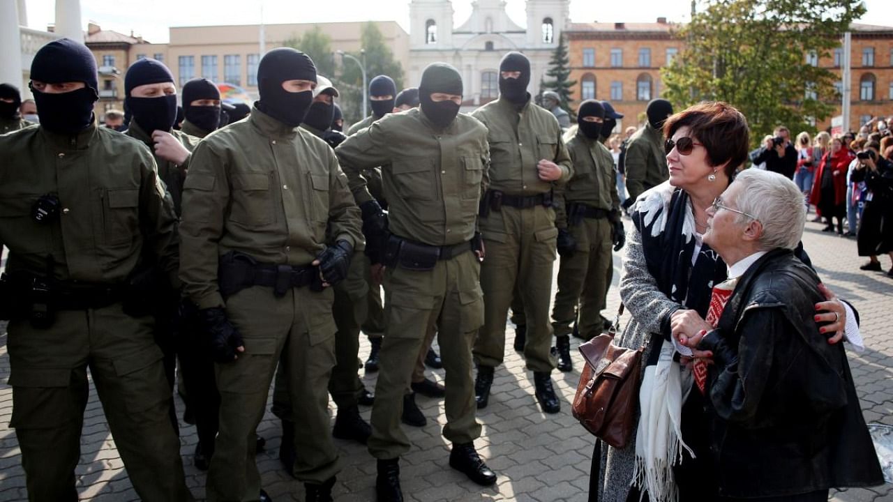 Opposition activist Nina Baginskaya (R), 73-year-old, and an unidentified woman stand in front of Belarus riot police officers during a rally to protest against the presidential election results in Minsk. Credit: AFP