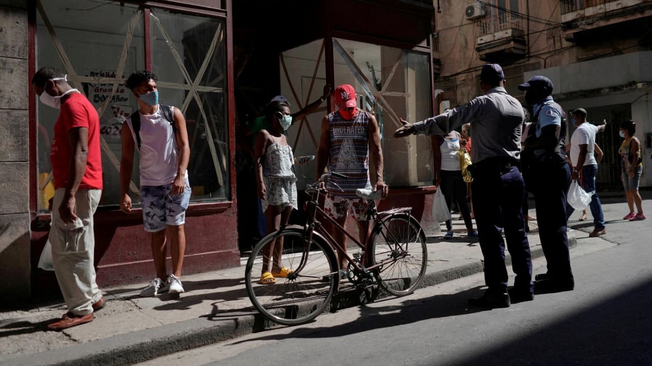 A police officer organizes a line of people waiting to buy food amid concerns about the spread of the coronavirus disease in Havana. Credit: Reuters/file photo