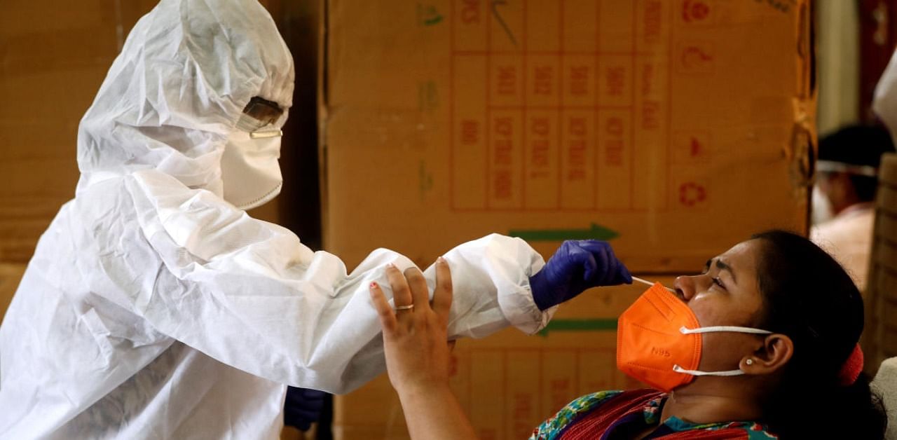 A health worker in personal protective equipment (PPE) collects a swab sample from a woman during a rapid antigen testing campaign for the coronavirus disease in Mumbai, India. Credit: Reuters